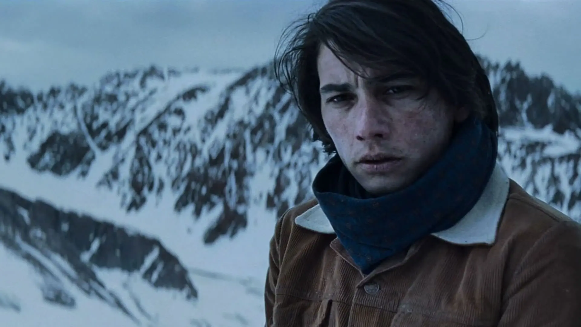 انزو ووگرینچیچ با لباسی گرم ایستاده در یک کوهستان برفی با چهره‌ای درهم به روبه‌رو نگاه می‌کند در نمایی از فیلم انجمن برف به کارگردانی جی ای بایونا