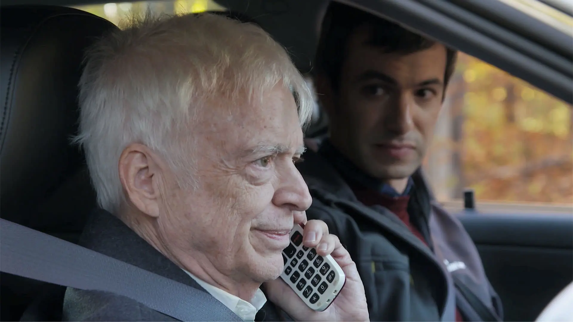 بیل هیث با تلفن حرف می‌زند در حالی که نیتن فیلدر داخل ماشین کنارش نشسته است در نمایی از قسمت پایانی سریال نیتن برای شما با نام یافتن فرانسیس